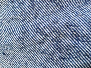 Denim Close-up of blue and white denim fabric showing a diagonal twill weave pattern, highlighting the textured, interlaced fibers and characteristic denim structure.