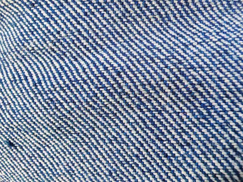Denim Close-up of blue and white denim fabric showing a diagonal twill weave pattern, highlighting the textured, interlaced fibers and characteristic denim structure.