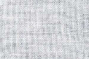 plain-weave Close-up of a white, textured fabric with a visible woven pattern and small intersecting threads, creating a grid-like appearance. The material appears natural and slightly uneven in texture.