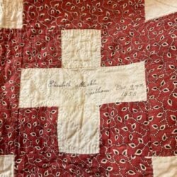 signature-block-1853 A section of a quilt features a red and white cross pattern. In the white center, “Elizabeth Michela, Chatham, Oct 27th 1858” is handwritten in cursive—a detail often used in Dating Antique or Vintage Quilts with paisley and geometric designs.