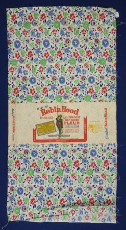 Robin-Hood-Flour A vintage flour sack with a colorful floral and leaf pattern in blue, green, and red, featuring a central Robin Hood all-purpose flour logo and branding in the middle.
