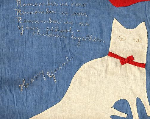 A piece of fabric art features a white cat with a red bow on a blue background, and hand-stitched text that reads: Remember us now, Remember us ever, Remember us as your school children together. Harry Ygeant.