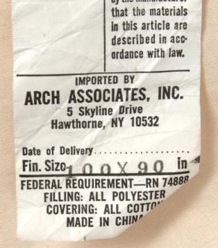 A white product tag from Arch Associates, Inc. lists the address, dimensions 100 x 90, filling as polyester, covering as cotton, federal requirement code RN 74888, and notes its made in China.