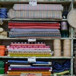 Photo by Magda Ehlers Organized shelves with various colorful fabrics, threads, and prices in a textile shop.