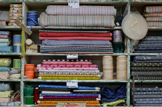 Photo by Magda Ehlers Organized shelves with various colorful fabrics, threads, and prices in a textile shop.