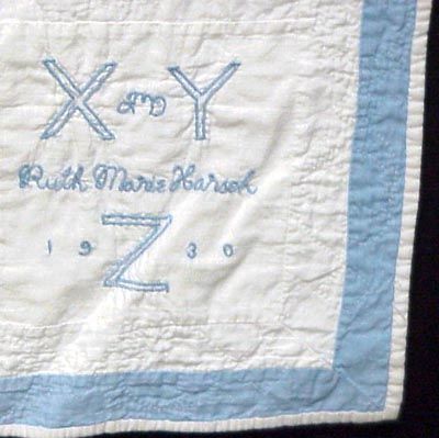 A white quilt with a light blue border, embroidered with large letters X Y Z, the name Ruth Marie Harsh, and the year 1930 in light blue thread.