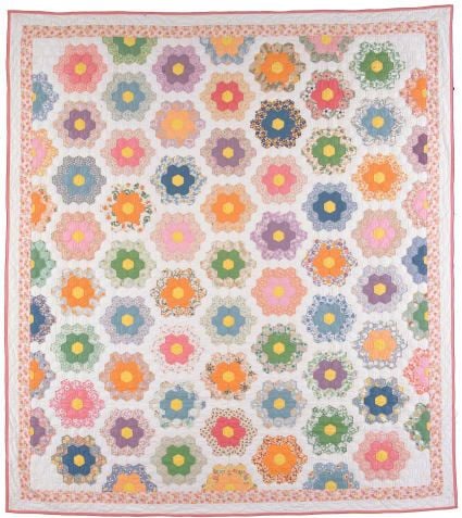 A handmade Grandmothers Flower Garden Quilt featuring colorful hexagonal flowers on a white background, each flower made of six petals around a center, bordered by a vibrant pink and orange floral design.