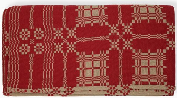 A folded woven textile featuring a red and beige geometric pattern with squares and lines, reminiscent of the Burgoyne Surrounded Quilt Block Myth, displayed against a white background.