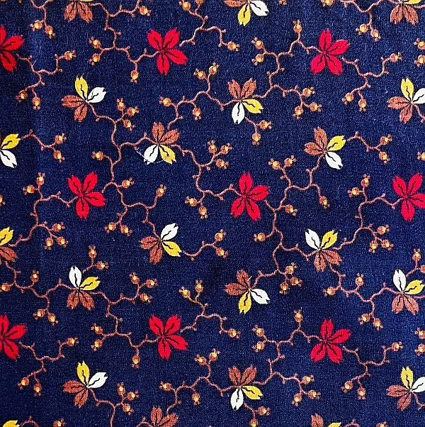 Navy blue fabric with a repeating floral pattern featuring red, yellow, and white flowers connected by thin, winding brown stems and small orange buds. The overall design is vibrant and intricate.