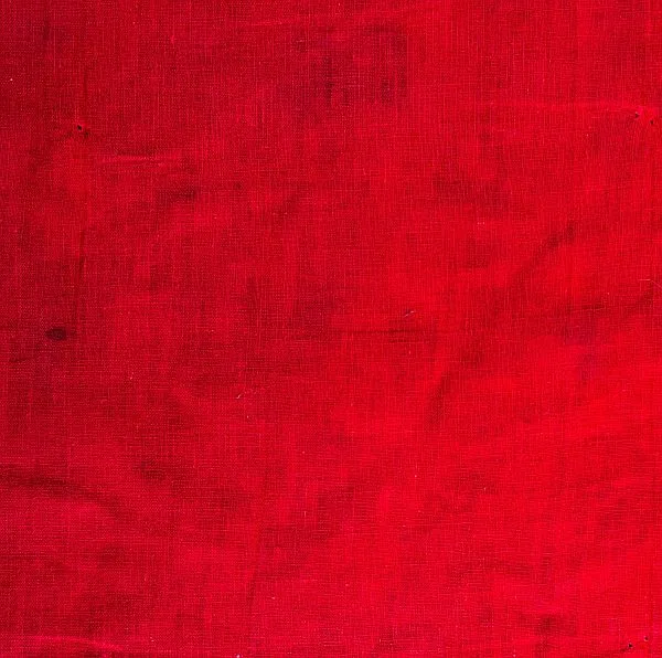A close-up of a red textured fabric, showing visible weave lines and slight creases throughout the surface.