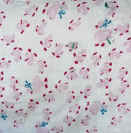 A fabric with a pattern of pink bunnies, some wearing blue or green bows, scattered among red stars on a white background.