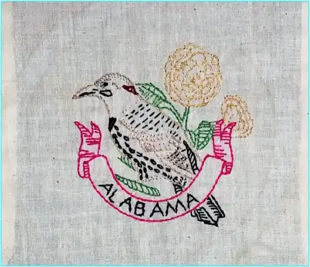 Embroidered image of a brown bird perched on a pink banner reading ALABAMA, with two yellow flowers behind it, on a light fabric background—perfect for State Birds and Flowers Outline Embroidery projects.