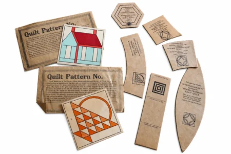 Grandmother-Clarks-cardboard-templates Assorted vintage quilt pattern templates, including paper instructions and illustrated pattern cards, arranged neatly on a white background.