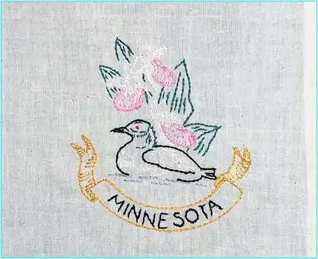 Embroidered loon with pink flowers and green leaves above it, and a yellow banner below reading MINNESOTA on light fabric—perfect for anyone who loves State Birds and Flowers Outline Embroidery.