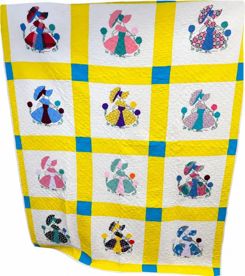 Sunbonnet-Sue-Quilt A quilt with a yellow and blue grid pattern featuring squares that each display an appliqué of a bonnet-wearing girl holding flowers, in various colorful dresses and hats—a charming design inspired by patterns preserved in the QHL Archives April 1997.