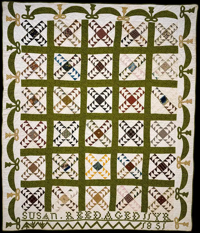 Wild_Goose_Chase_Quilt_1851-MET A patchwork quilt with a green lattice design, various patterned squares, decorative border, and the text SUSAN R. REED AGED 17 YR 1851 stitched at the bottom.