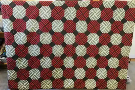 This was a quilt backing. It is a Cheater-cloth backing printed with repeating red-and-black and green-and-black octagons on a gray background.