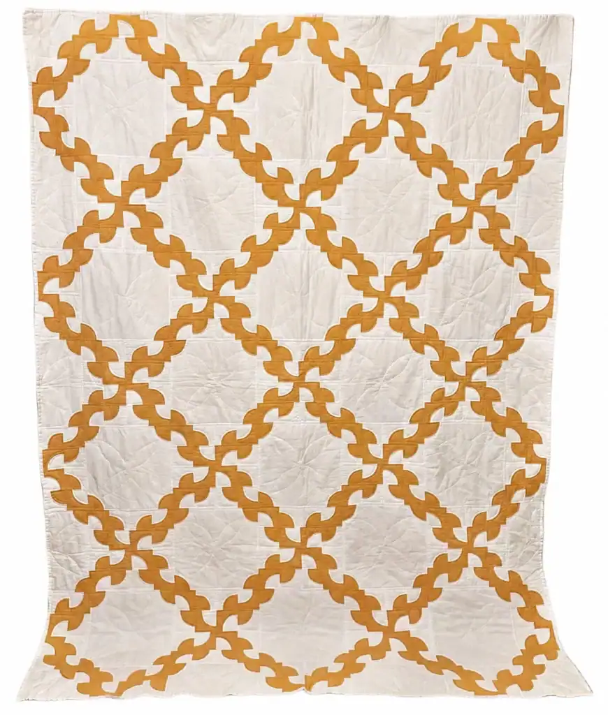 yellow-and-white-drunkards-path A quilt with a white background and an interlocking gold or yellow chain pattern forming diamond shapes across the surface.
