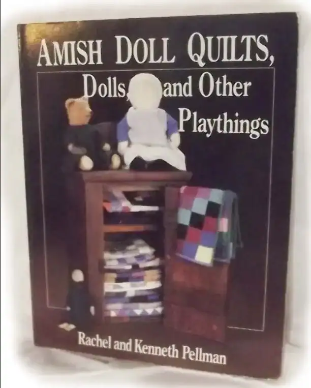 Book cover of Amish Doll Quilts, Dolls, and Other Playthings by Rachel and Kenneth Pellman, featuring handmade dolls and a cabinet with colorful folded quilts.