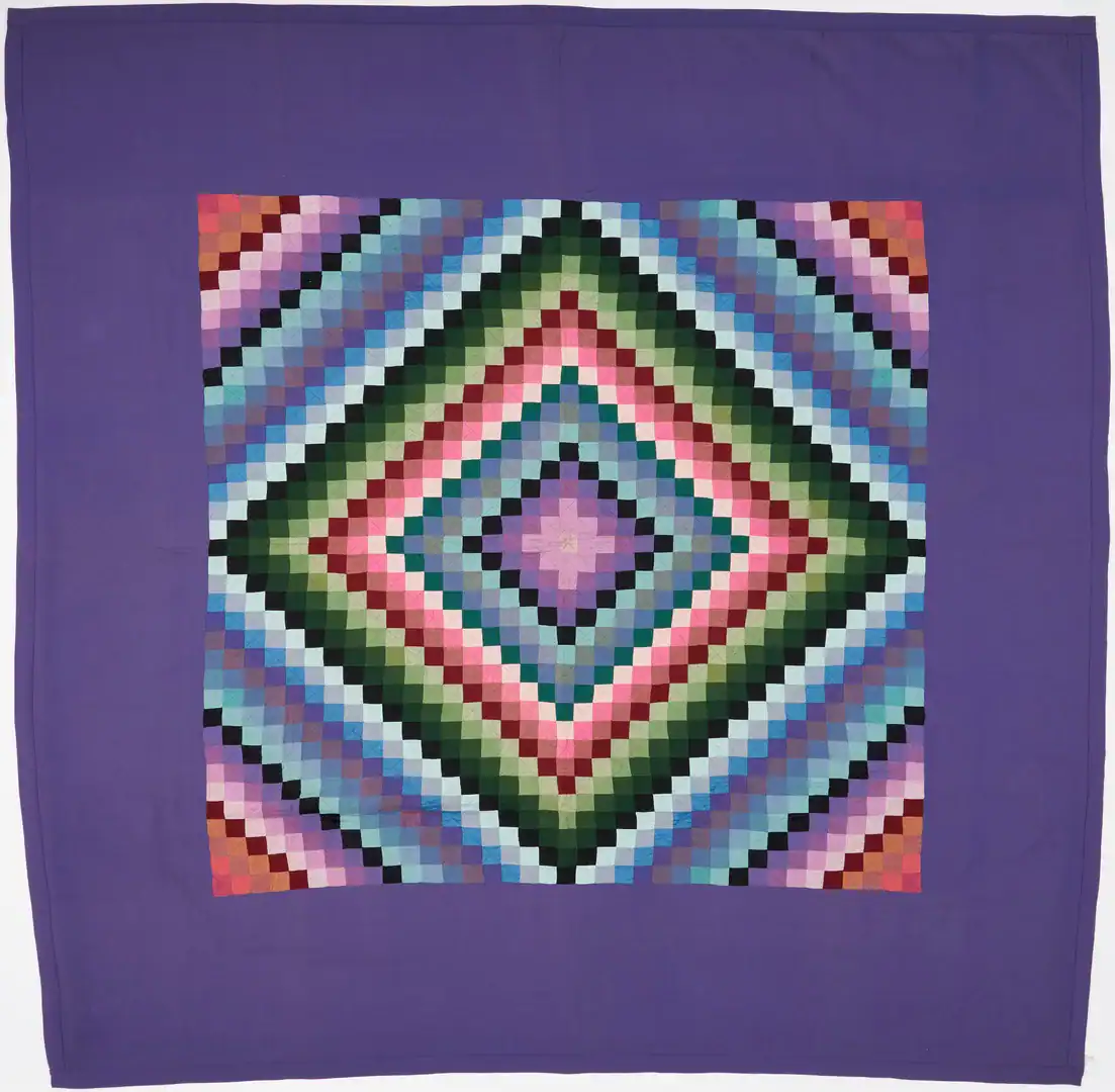 Sunshine-and-Shadows-Amish-Quilt A quilt with a purple border and a central diamond pattern made of small, colorful squares arranged in concentric, gradient bands from pink and purple to green, blue, and black.