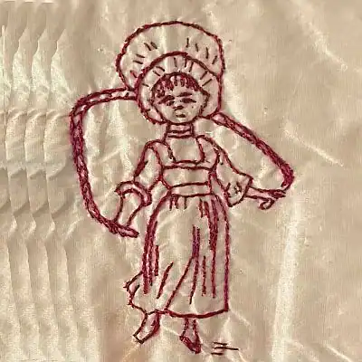 Red embroidery of a girl wearing a bonnet and dress on cream fabric. She stands with arms slightly out, and the stitching shows simple details for her features and clothes.