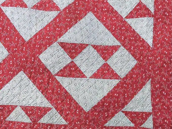 Close-up of red print triangles and white sashing on the red and white quilt top