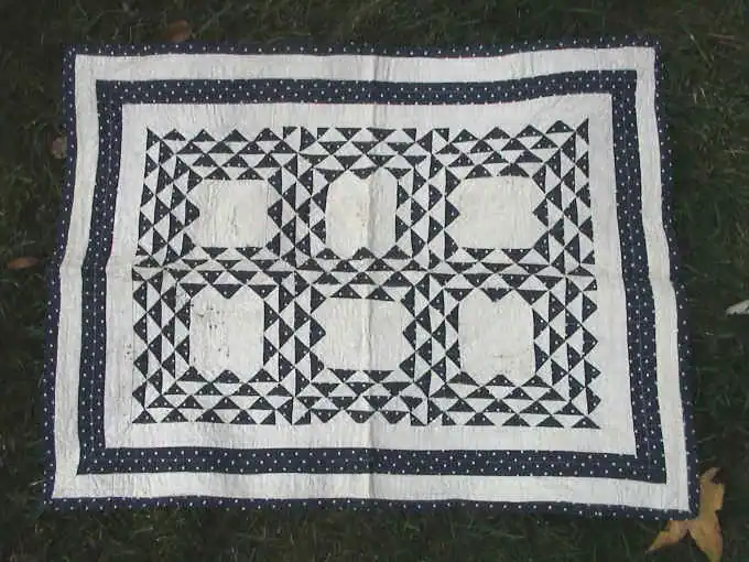 Small indigo and white doll quilt dated 1878, with pieced triangle blocks and a blue border