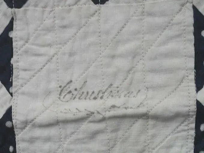 Ink word Christmas written in a white block of the 1878 doll quilt