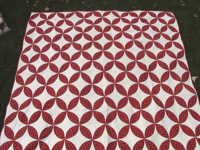 Red and white Orange Peel quilt laid on grass